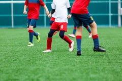 Chłopiec w czerwonym białym sportswear bieg na boisku do piłki nożnej Młodzi futboliści dryblują futbolową piłkę w grą i kopią sz obraz royalty free Chłopiec w czerwonym białym sportswear bieg na boisku do piłki nożnej Młodzi futboliści dryblują futbolową piłkę w grą i kopią sz obraz royalty free