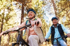 Ciclismo di montagna senior delle coppie su una traccia della foresta, angolo basso Fotografia Stock Ciclismo di montagna senior delle coppie su una traccia della foresta, angolo basso Fotografia Stock