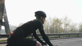 Ciclista apto magro que monta uma bicicleta sob a ponte O verso segue o tiro da bicicleta pedaling do cavaleiro da bicicleta na e video estoque Ciclista apto magro que monta uma bicicleta sob a ponte O verso segue o tiro da bicicleta pedaling do cavaleiro da bicicleta na e video estoque