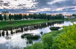 Cielo drammatico di tramonto sopra il fiume di Tvertsa e le sue rive pittoresche dopo la tempesta Città provinciale russa Toržok, Fotografie Stock Cielo drammatico di tramonto sopra il fiume di Tvertsa e le sue rive pittoresche dopo la tempesta Città provinciale russa Toržok, Fotografie Stock