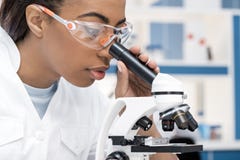 Cientista afro-americano no revestimento do laboratório que trabalha com o microscópio no laboratório químico Imagem de Stock Cientista afro-americano no revestimento do laboratório que trabalha com o microscópio no laboratório químico Imagem de Stock