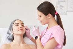 Cierpliwy atrakcyjny klient kłama w kosmetycznym krześle, być spokojem, fachowy beautician jest ubranym różowego lab żakiet z mąd obrazy stock Cierpliwy atrakcyjny klient kłama w kosmetycznym krześle, być spokojem, fachowy beautician jest ubranym różowego lab żakiet z mąd obrazy stock