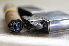 Cigarro apenas ahumado y encendedor de la gasolina Foto de archivo libre de regalías Cigarro apenas ahumado y encendedor de la gasolina Foto de archivo libre de regalías