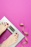 Cinta y escalas de la medida en un fondo rosado con el exceso de peso de las palabras Mujeres del plan y del entrenamiento de la imágenes de archivo libres de regalías Cinta y escalas de la medida en un fondo rosado con el exceso de peso de las palabras Mujeres del plan y del entrenamiento de la imágenes de archivo libres de regalías
