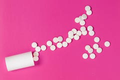 Circle pills tablets spilling out of a white plastic medicine bottle on pink background royalty free stock photo Circle pills tablets spilling out of a white plastic medicine bottle on pink background royalty free stock photo