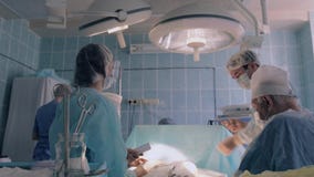 Cirurgião que gira a luz sob o ângulo correto para continuar a cirurgia video estoque Cirurgião que gira a luz sob o ângulo correto para continuar a cirurgia video estoque