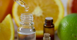 Citrus essential oil dripping from pipette on fresh fruit background