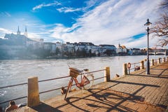 City bicycle with basket on the steering wheel of red color on the quay near the river Rhine in Switzerland against the backdrop o stock photos City bicycle with basket on the steering wheel of red color on the quay near the river Rhine in Switzerland against the backdrop o stock photos