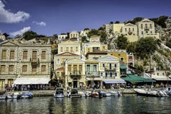 Greek island with pastel colored houses under clear blue skies. City center of the Greek island of Symi with pastel colored houses under clear blue skies, Agean Royalty Free Stock Photography Greek island with pastel colored houses under clear blue skies. City center of the Greek island of Symi with pastel colored houses under clear blue skies, Agean Royalty Free Stock Photography