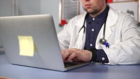 Ciérrese encima de tiro del médico de sexo masculino moderno en la capa blanca usando el ordenador portátil almacen de video Ciérrese encima de tiro del médico de sexo masculino moderno en la capa blanca usando el ordenador portátil almacen de video