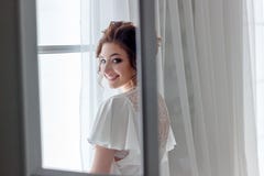 Ciérrese encima del retrato de la señora joven hermosa que se relaja en la ventana y en la cámara de mirada feliz foto de archivo Ciérrese encima del retrato de la señora joven hermosa que se relaja en la ventana y en la cámara de mirada feliz foto de archivo