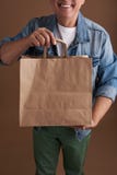 Ciérrese para arriba de la bolsa de papel en manos de la persona sonriente foto de archivo libre de regalías Ciérrese para arriba de la bolsa de papel en manos de la persona sonriente foto de archivo libre de regalías