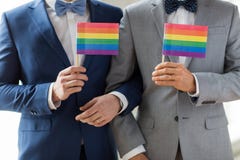Ciérrese para arriba de los pares gay masculinos que sostienen banderas del arco iris Imágenes de archivo libres de regalías Ciérrese para arriba de los pares gay masculinos que sostienen banderas del arco iris Imágenes de archivo libres de regalías