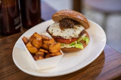 Ciérrese para arriba de una hamburguesa hecha en casa con las patatas picantes foto de archivo Ciérrese para arriba de una hamburguesa hecha en casa con las patatas picantes foto de archivo