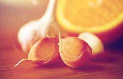 Ciérrese para arriba del ajo y de la naranja en la tabla de madera foto de archivo Ciérrese para arriba del ajo y de la naranja en la tabla de madera foto de archivo