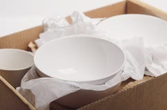 Clean white dishes in paper packed in a cardboard box. Concept relocation stock photos Clean white dishes in paper packed in a cardboard box. Concept relocation stock photos