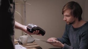 Cliente hermoso del hombre que paga por la tarjeta de crédito sin contacto en café moderno almacen de metraje de vídeo Cliente hermoso del hombre que paga por la tarjeta de crédito sin contacto en café moderno almacen de metraje de vídeo