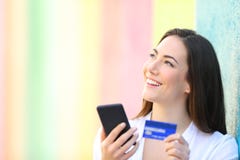 Cliente online che pensa tenendo telefono e la carta di credito fotografia stock libera da diritti Cliente online che pensa tenendo telefono e la carta di credito fotografia stock libera da diritti