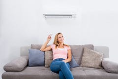Climatiseur fonctionnant de femme avec à télécommande images stock Climatiseur fonctionnant de femme avec à télécommande images stock