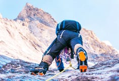 Climber Reaches The Summit Of Mountain Peak. Climbing And Mountaineering Sport Concept Stock Photo