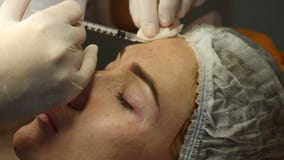 Clinica di bellezza Mani dell'estetista in guanti che fanno l'iniezione di invecchiamento del fronte in una pelle femminile Una d stock footage Clinica di bellezza Mani dell'estetista in guanti che fanno l'iniezione di invecchiamento del fronte in una pelle femminile Una d stock footage