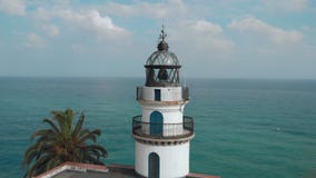 Close clockwise aerial shot of lighthouse on the coast above the ocean with the ocean in the background in Catalonia stock video Close clockwise aerial shot of lighthouse on the coast above the ocean with the ocean in the background in Catalonia stock video