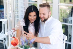 Close-up of beautiful young people sitting in a cafe, taking a photo on the phone. A man makes a selfie with his happy stock photos Close-up of beautiful young people sitting in a cafe, taking a photo on the phone. A man makes a selfie with his happy stock photos