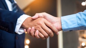 Close up businessmen shaking hands during a meeting. Handshake deal business corporate