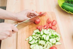 Close-up Delicate Female Hands Cut A Large Knife With Tomatoes On A Quarter On A Wooden Board At Home. Home Kitchen Stock Photos
