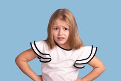 Close up emotional portrait of young blonde girl on blue background in studio. She holds her hands at the waist and is royalty free stock images Close up emotional portrait of young blonde girl on blue background in studio. She holds her hands at the waist and is royalty free stock images