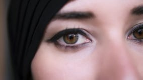 Close-up extremo de uma mulher mu?ulmana do Oriente M?dio nova no hijab preto que abre os olhos marrons e que olha ? c?mera vídeos de arquivo Close-up extremo de uma mulher mu?ulmana do Oriente M?dio nova no hijab preto que abre os olhos marrons e que olha ? c?mera vídeos de arquivo