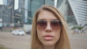 Close up fashion and glamour beautiful woman portrait wearing sunglasses. A girl with lush lips against the background stock footage Close up fashion and glamour beautiful woman portrait wearing sunglasses. A girl with lush lips against the background stock footage