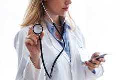 Female medical doctor holding stethoscope and using her smartphone over white background royalty free stock image Female medical doctor holding stethoscope and using her smartphone over white background royalty free stock image