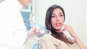 Close up of female patient talking with dentist and showing aching tooth