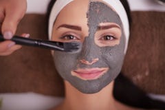 Close up of hand applying facial mask to woman face at beauty salon