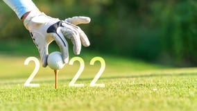 Close up hand Golfer woman putting golf ball for Happy New Year 2022 on the green golf for new healthy.