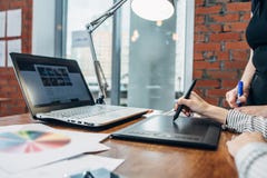 Close-up image of women drawing a project using a graphic tablet and a laptop sitting in modern office royalty free stock photos Close-up image of women drawing a project using a graphic tablet and a laptop sitting in modern office royalty free stock photos
