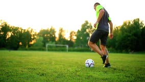 Close up legs and feet of football player in action wearing black shoes running and dribbling with the ball playing on