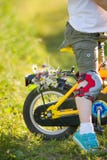 Close up of little kid boy riding on his bicycle with flowers, outdoors. Boy riding his first yellow bike on a meadow royalty free stock photo Close up of little kid boy riding on his bicycle with flowers, outdoors. Boy riding his first yellow bike on a meadow royalty free stock photo