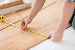 Close up of male hands measuring wood flooring