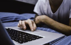 Close up of man`s hands using computer, surfing on internet and relaxing on bed royalty free stock images Close up of man`s hands using computer, surfing on internet and relaxing on bed royalty free stock images