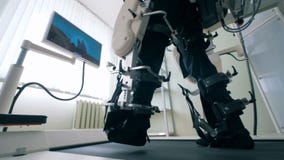 Close up of man`s legs in bonds of a training machine during walking exercises. Electronic medical robotic for stock footage Close up of man`s legs in bonds of a training machine during walking exercises. Electronic medical robotic for stock footage