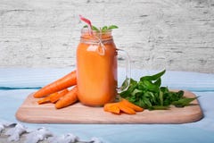 Close-up of a nutritious vitamin cocktail. Big mason jar filled with thick carrot beverage on a gray table background. stock photography Close-up of a nutritious vitamin cocktail. Big mason jar filled with thick carrot beverage on a gray table background. stock photography