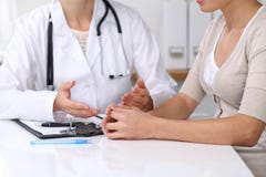 Close Up Of Doctor And Patient Sitting At The Desk While Physician Pointing Into Medical Form Hystory. Medicine A Stock Photos
