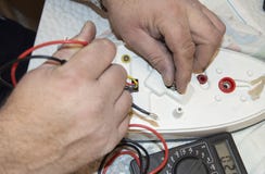 Close-up of the old electrician`s hand, the use of digital voltmeter for voltage to repair the electric iron, selective stock image Close-up of the old electrician`s hand, the use of digital voltmeter for voltage to repair the electric iron, selective stock image