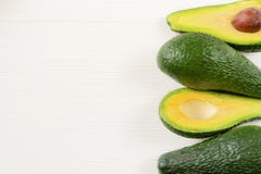 Close-up photo of avocados cut to half, brown seeds visible, with more avocados on white wooden background. royalty free stock photo Close-up photo of avocados cut to half, brown seeds visible, with more avocados on white wooden background. royalty free stock photo
