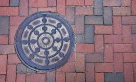 A rustic manhole cover on a brick sidewalk. royalty free stock photography A rustic manhole cover on a brick sidewalk. royalty free stock photography