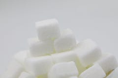 Close up A pile of brown sugar cubes on a white plate five wooden letter character on white background royalty free stock photography Close up A pile of brown sugar cubes on a white plate five wooden letter character on white background royalty free stock photography