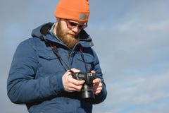 Close-up portrait bearded male photographer in sunglasses with dslr camera in his hands looks at the photos on the royalty free stock photo Close-up portrait bearded male photographer in sunglasses with dslr camera in his hands looks at the photos on the royalty free stock photo