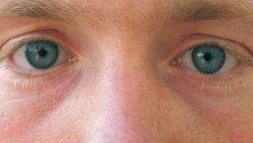 Close up of sad male blue eyes blinking and looking into camera with daylight. Portrait of young handsome man watching stock video footage Close up of sad male blue eyes blinking and looking into camera with daylight. Portrait of young handsome man watching stock video footage